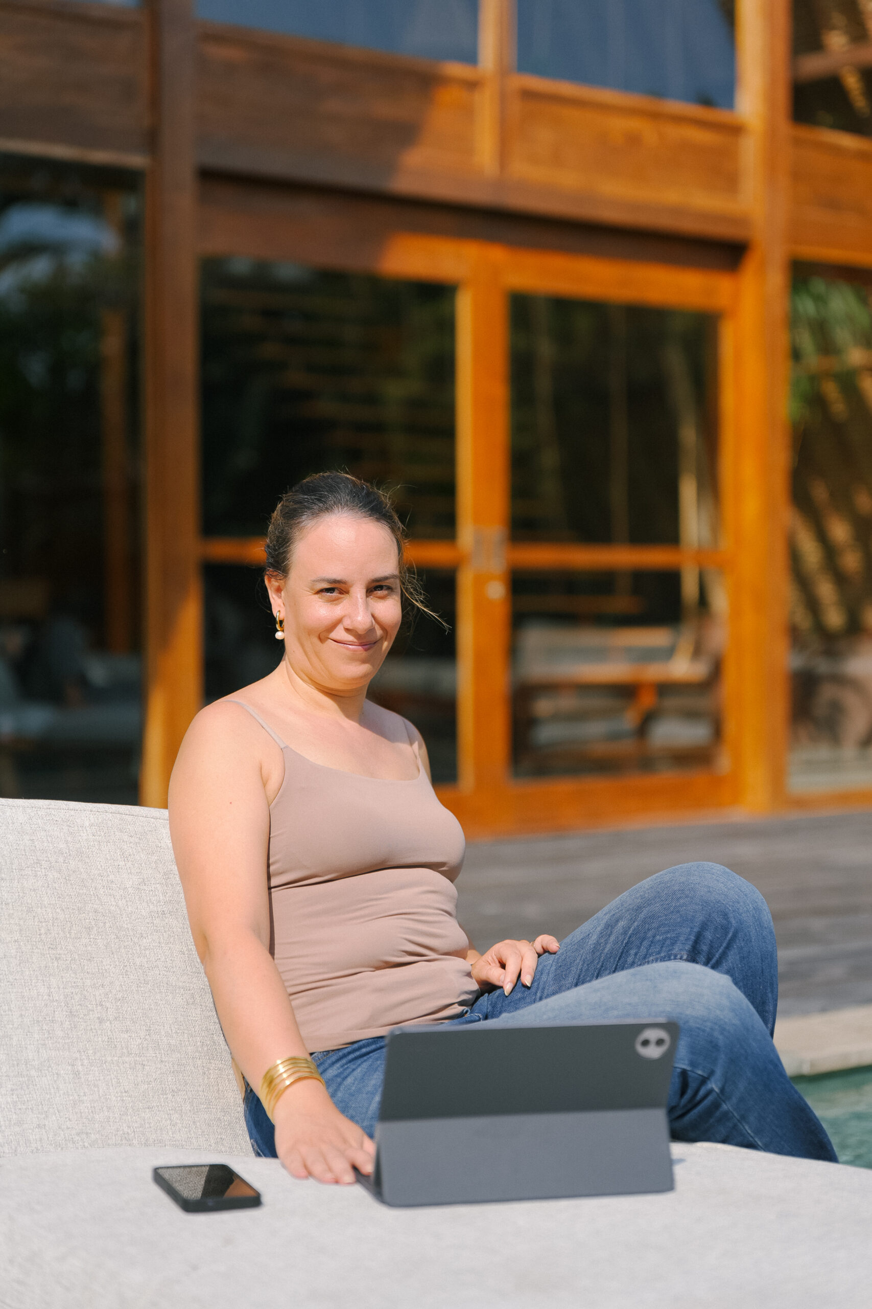Sophia Benarafa, business mentor and founder of The Academy by Sophia, working from a tablet beside a pool